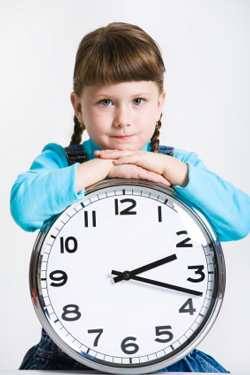 Girl standing next to a clock